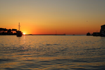 Sunset with boat silhouettes on the Adriatic sea in Porec, Istria, Croatia, Europe. Beautiful sunset by the Adria sea, The sun is setting over the sea, Porec