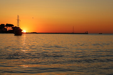 Sunset with boat silhouettes on the Adriatic sea in Porec, Istria, Croatia, Europe. Beautiful sunset by the Adria sea, The sun is setting over the sea, Porec