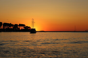 Sunset with boat silhouettes on the Adriatic sea in Porec, Istria, Croatia, Europe. Beautiful sunset by the Adria sea, The sun is setting over the sea, Porec