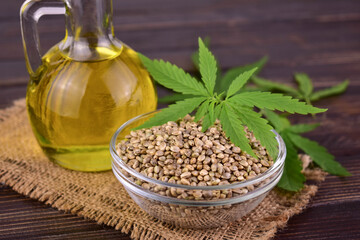 Healthy hemp oil and hemp seeds on wooden background.	Close-up.
