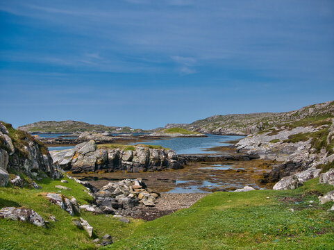 A rocky bay on the coast the island of Bernera (Great Bernera) in Loch Roag on the north-west coast of Lewis in the Outer Hebrides, Scotland, UK. Taken on sunny day with a blue sky in summer.