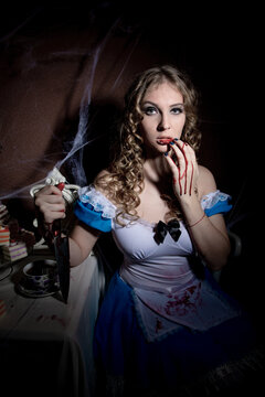 Halloween. Portrait of a young woman with a large kitchen knife. Dressed as Alice