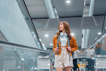 Happy attractive asian woman traveler with backpack at the modern airport terminal, copy space,...