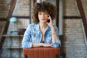 Serious young woman wearing denim jacket sitting on leather chair