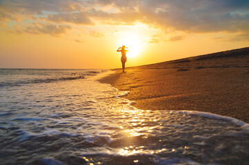 Seascape during golden sunrise or sunset with beautiful sky. Woman on the beach. Young happy woman...