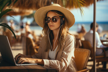Business woman working with computer on the beach. Freelance concept. Pretty young woman using laptop in cafe on tropical beach. Technology and travel.
