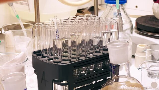 A research scientist preparing samples in clean NMR tubes from reaction mixture in a chemistry laboratory for biotechnology research and drug development