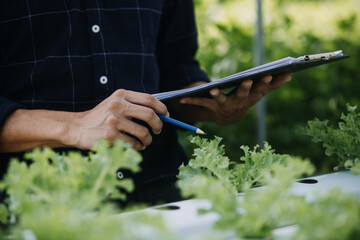 In the Industrial Greenhouse Two Agricultural Engineers Test Plants Health and Analyze Data with Tablet Computer.