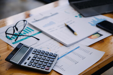 Obraz premium Asian Businesswoman Using laptop computer and working at office with calculator document on desk, doing planning analyzing the financial report, business plan investment, finance analysis concept.