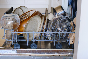 Full dishwasher tray after washing dishes, clean utensil close up