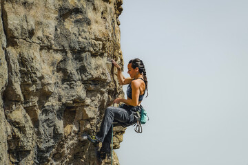 Fototapeta premium Courageous Female Climber Ascending a Steep Cliff