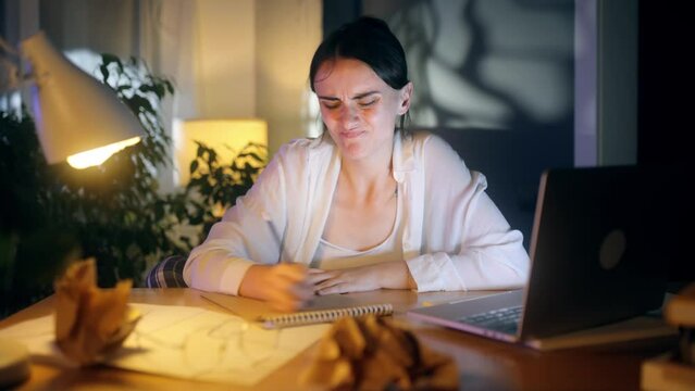 Sad young woman student or freelancer with lack of new ideas or creative block writing and crossed out at home Worried female with crumpled papers with failed ideas working or studying indoors