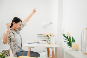 Portrait of happy freelance Asian woman working at home feeling excited and extremely happy with...