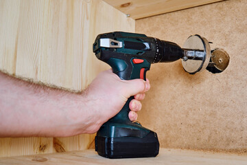 Drilling round holes with a crown on the drill bit. Sawing furniture with a circular saw with a nozzle on an electric screwdriver