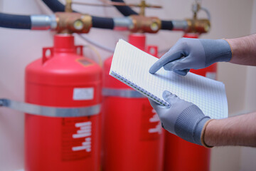 The inspector of fire security is using his notepad to jot down notes as he checks the fire...