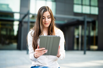 Young businesswoman using a digital tablet outdoor sitting on a bench