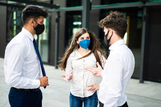Business partners discussing together outdoor wearing a protective mask against covid 19 coronavirus pandemic