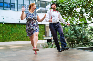Cheerful couple dressed in vintage clothes dancing retro swing dance to jazz music which was very...