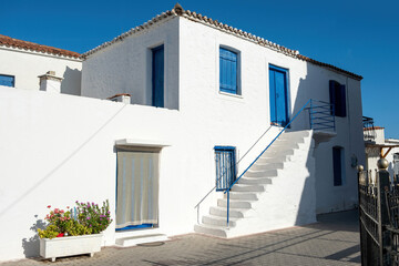 Agistri island Megalochori, Milos Miloi village Greece. Whitewashed building stair, blue door window