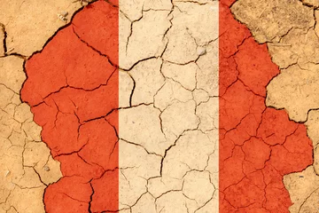 Fotobehang Drought. On dry, cracked ground, the image of the flag of Peru. © Dzmitry