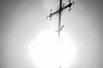 The Orthodox carved cross made of black metal looks like a ghost against the gray sky, almost...