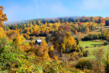 Obraz premium Old barn amongst hills of colorful autumn leaves in the countryside near Woodstock, Vermont, USA