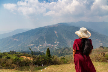A female tourist enjoys view of scenic, misty Himalayan mountain landscape at Darjeeling, West Bengal, India. 