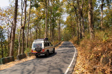 A tourist vehicle travels along a scenic mountain road on way to Darjeeling in West Bengal, India