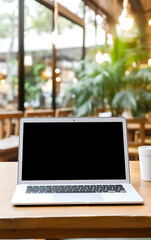 Laptop blank screen on table in cozy coworking space, remote work or freelancing concept