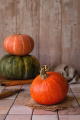 Autumn minimalist composition: three ripe pumpkins of different varieties on a light beige background. Harvest season. Farm organic products. Vertical photo. Place for text.