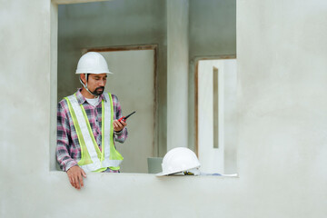 Spanish engineer Using radio communication Talk to the foreman To order work. Man standing using...