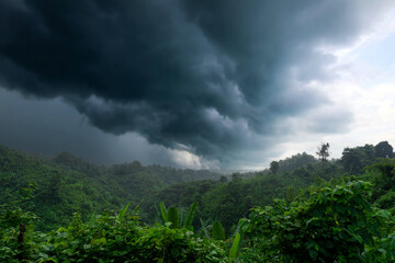 During the rainy season, thick green hills are mixed with thick black clouds in the sky. Hilly region of Bandarban district of Bangladesh. - obrazy, fototapety, plakaty