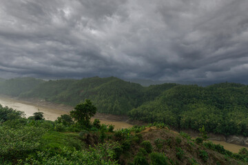 Obraz premium During the rainy season, the thick green hills blend into the thick black clouds in the sky. Sangu river flows below. Hilly region of Bandarban district of Bangladesh.