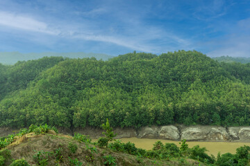 Fototapeta na wymiar During the rainy season, the dense green hills blend into the blue sky. Sangu river flows below. Hilly region of Bandarban district of Bangladesh.