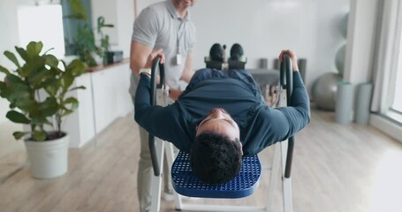 Inversion, table and man in therapy for back pain, healing and stretching spinal muscle with chiropractor in healthcare clinic. Physiotherapy, rehabilitation and patient stretch in spine with doctor