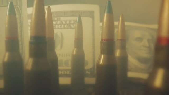Rifle cartridges on the background of dollar bills in clouds of smoke close up. The concept of the sale of weapons under lendlease, help with weapons, hired work in the army, ammunition trade.