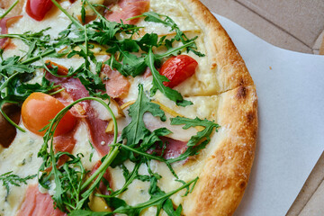 Freshly baked pizza with arugula, tomatoes, meat and cheese. Nutrition concept