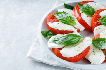Salad Caprese with tomato, mozzarella and basil on gray background. Top view. Copy space