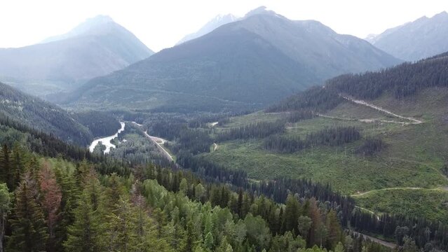 Aerial Valley Landscape View - Pan Left - British Columbia Rocky Mountains. Valley scenery: Mountains, Lake, Clouds, Sky, Trees, Forest. Beautiful British Columbia.