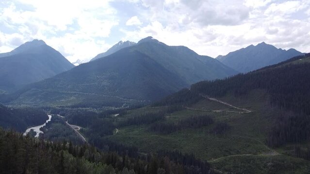 3 Mountain Peaks Ascending Aerial Landscape Drone View. A breathtaking vista of a pristine lake and lush valley, surrounded by majestic mountains, conjures a sense of awe and wonder in BC, Canada.