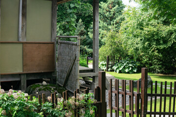 landscape of a traditional Japanese garden with plants, paths and a fragment of a pavilion