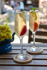 Fruity cocktails with ice in standing champagne glasses, close-up.