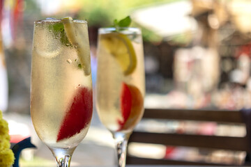Fruity cocktails with ice in standing champagne glasses, close-up.