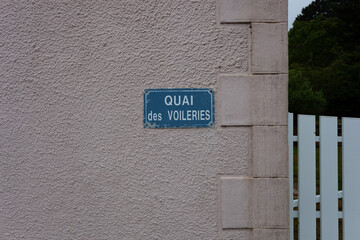 A street sign on a white wall.