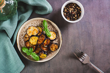 Appetizing fried eggplant with spices and herbs on a plate on the table top view