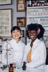 Two multicultural pharmacists standing in a vintage pharmacy