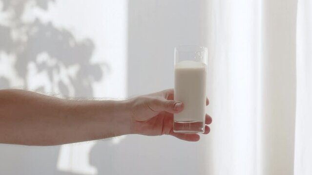 A man holds a glass of milk on a white background. Dairy product in a male hand. Dairy breakfast