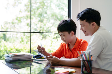 Father helping son doing homework at home..