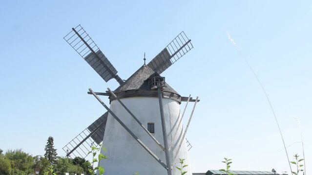 Old windmill, blades spinning in the wind, rural landscape, blue sky, Europe, Austria.