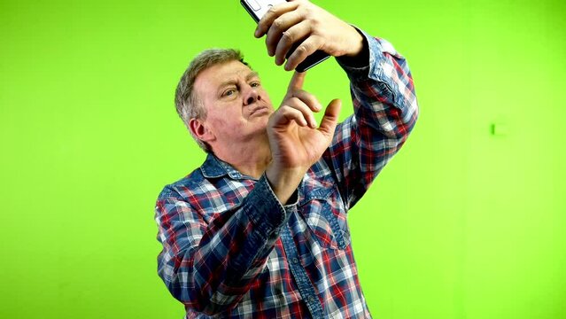 Funny senior caucasian man taking silly selfie using his smartphone.
